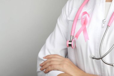 Pembe kurdele ve gri arka plan, metin için yer üzerinde stetoskop ile doktor. Meme Kanseri Bilinçlendirme