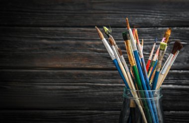 Boya fırçaları ahşap arka plan üzerinde ile jar. Metin için yer