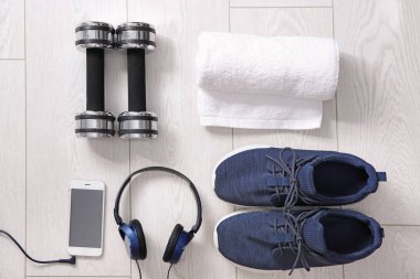Spor ayakkabı, kulaklık, cep telefonu, havlu ve ahşap arka plan üzerinde dumbbells ile düz yatıyordu kompozisyon