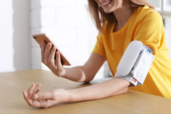 Frau Checkt Blutdruck Mit Modernem Monitor Und Smartphone Tisch Drinnen — Stockfoto