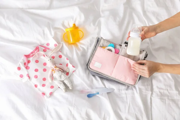 Γυναίκα Συσκευασίας Αξεσουάρ Μωρό Τσάντα Μητρότητας Στο Κρεβάτι Top View — Φωτογραφία Αρχείου
