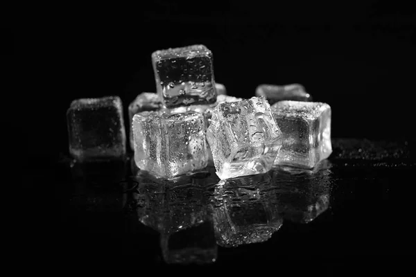 Pile of crystal clear ice cubes on black background