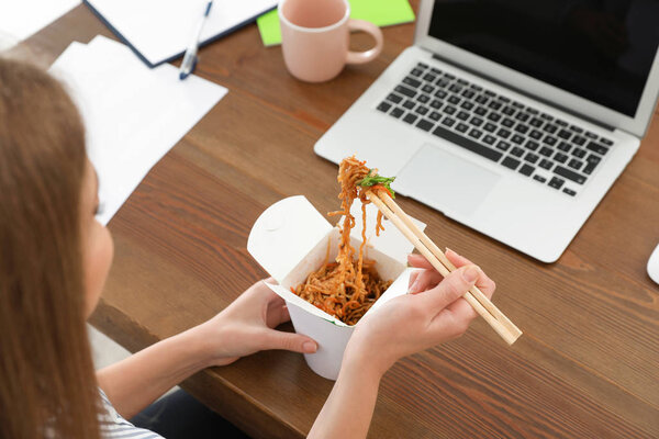 Office employee having noodles for lunch at workplace, closeup. Food delivery