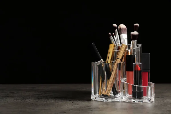 口红持有人与不同的化妆产品在桌子上对黑色背景 文本的空间 — 图库照片
