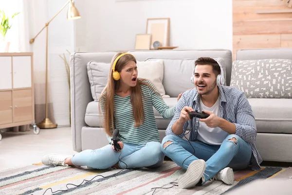 Emotional young couple playing video games at home