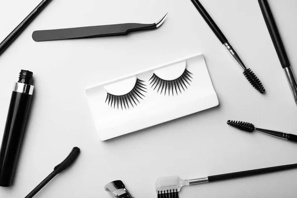 Artificial eyelashes and accessories on grey background, flat lay