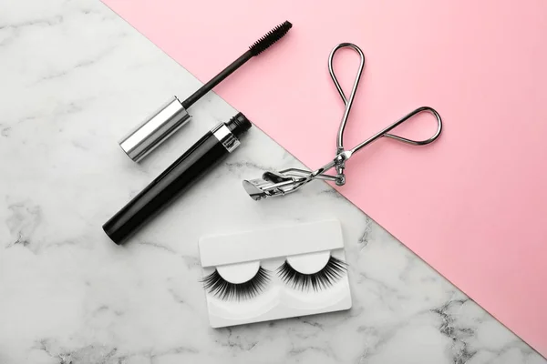 Artificial eyelashes and accessories on color background, flat lay