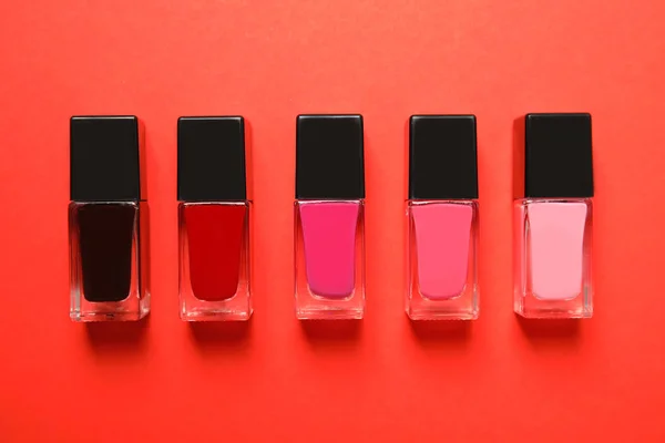 Bottles of nail polish on color background, top view