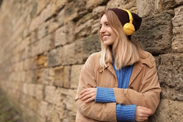 石の壁に近い音楽を聴くヘッドフォンを持つ若い女性 テキストのためのスペース — ストック写真