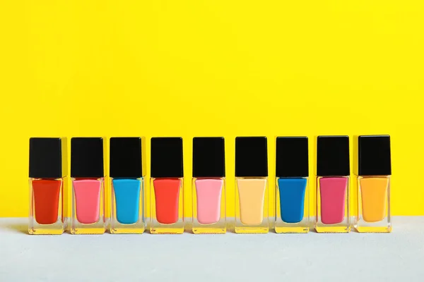Bright nail polishes on table against color background. Space for text