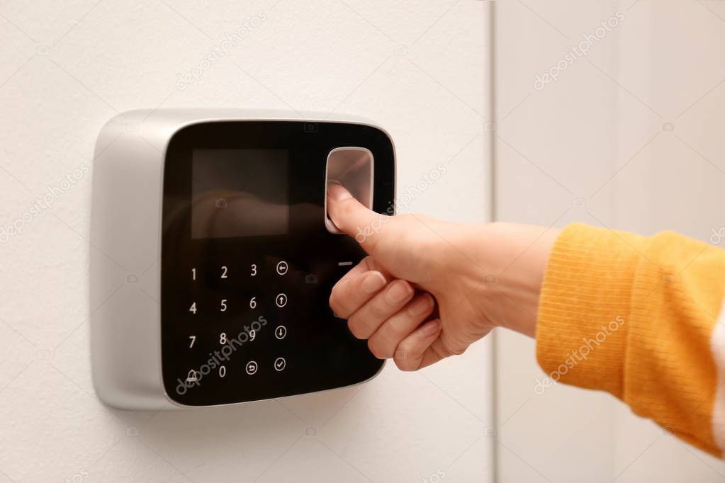 Woman scanning fingerprint on alarm system indoors, closeup