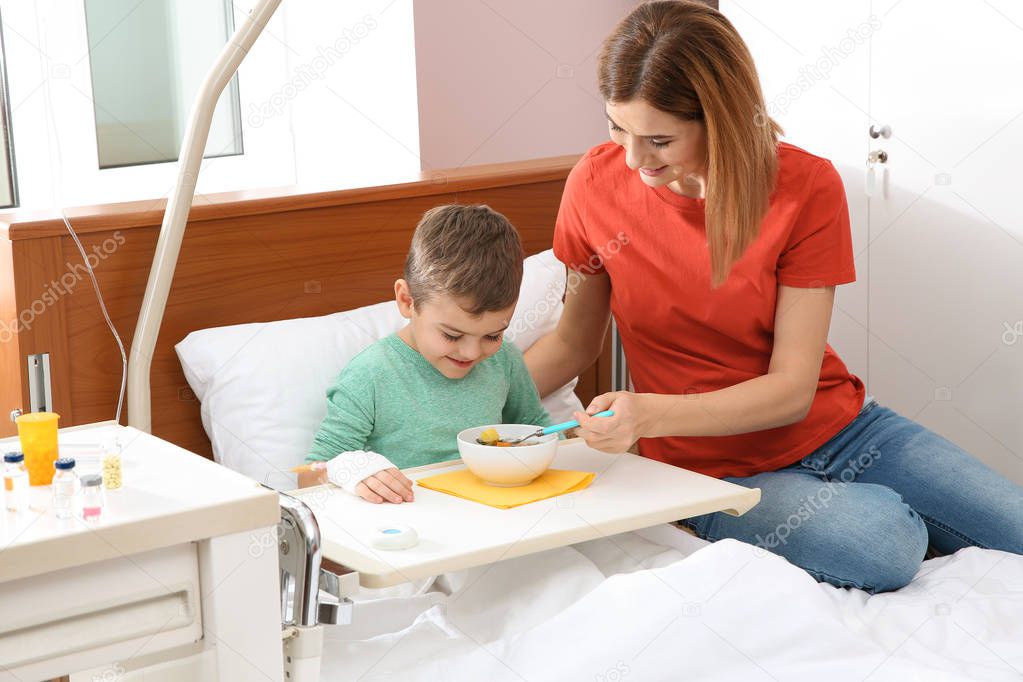 Woman feeding her little child with soup in hospital