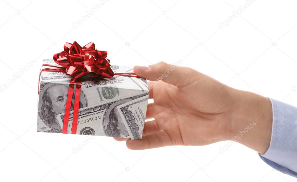 Man holding gift box wrapped in decorative paper with dollar pattern on white background, closeup