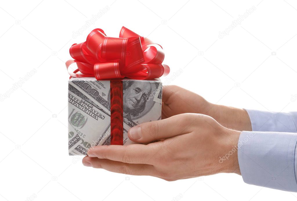 Man holding gift box wrapped in decorative paper with dollar pattern on white background, closeup