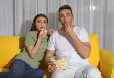 Oturma odasında kanepede birlikte Tv izlerken patlamış mısır ile Çift