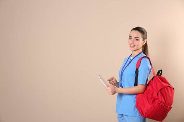 Tablet ve renk arka plan üzerinde sırt çantası ile genç tıp öğrencisi. Metin için yer