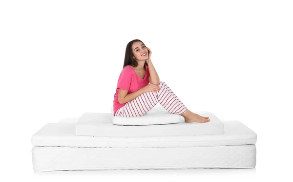 年轻的妇女坐在床垫堆在白色背景 — 图库照片