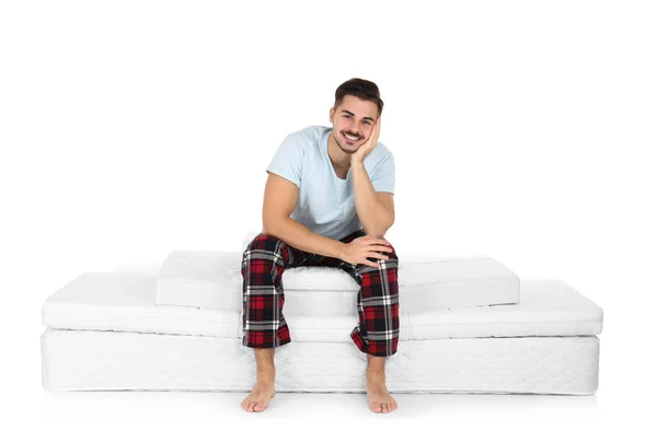Junger Mann Sitzt Auf Matratzenstapel Vor Weißem Hintergrund — Stockfoto