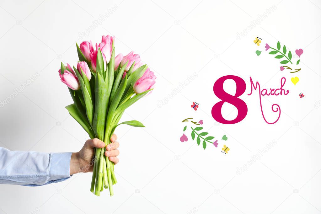 Man holding bouquet of beautiful spring tulips and text 8 March on light background, closeup. International Women's Day