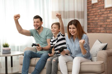 Mutlu aile oturma odasında kanepede video oyunları oynarken
