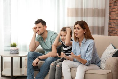 Oturma odasında kanepede video oyunları oynarken aile