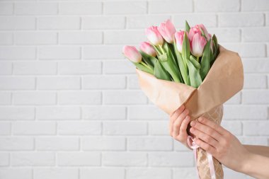 Buket tuğla duvar yakınındaki güzel bahar laleler, closeup ile metin için yer tutan kız. Dünya Kadınlar Günü