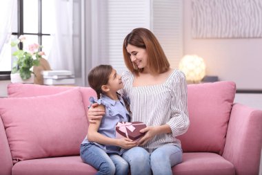 Mutlu anne ve kızı kanepe evde hediye ile. Dünya Kadınlar Günü