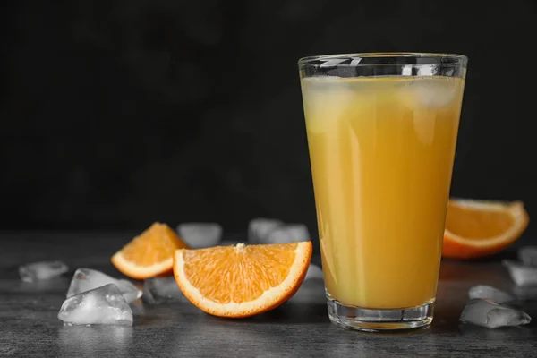 Glas Sinaasappelsap Met Ijsblokjes Gesneden Fruit Tafel Tegen Zwarte Achtergrond — Stockfoto