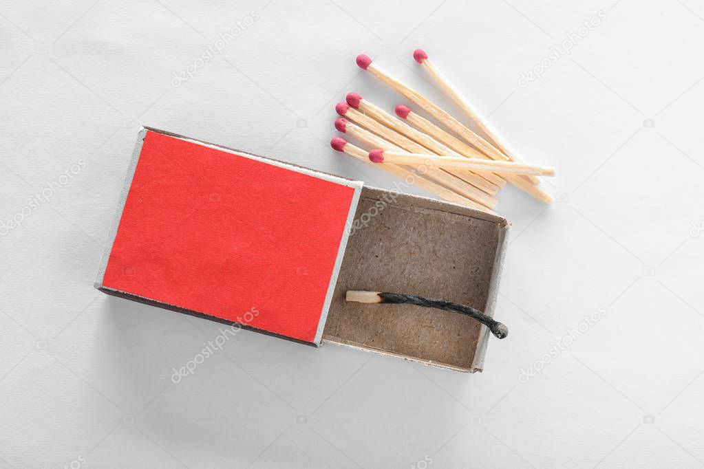 Cardboard box with burnt match and whole ones on white background, top view. Space for design
