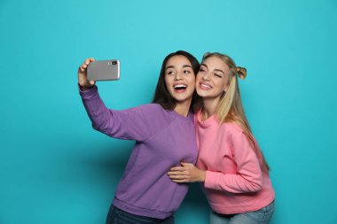 Genç kadın selfie renk arka plan karşı çekerken gülüyor