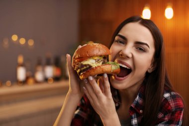Genç kadın kafede lezzetli hamburger yemek