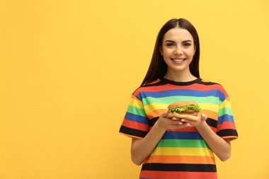 Lezzetli burger renkli arka plan üzerinde olan kadın. Metin için yer