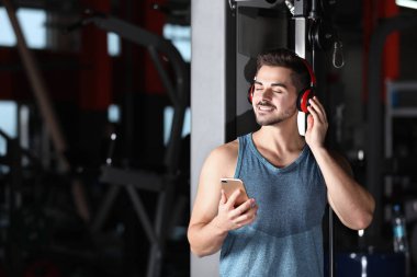 Genç adam kulaklıklarla müzik üstünde hareket eden aygıt vasıl jimnastik salonu