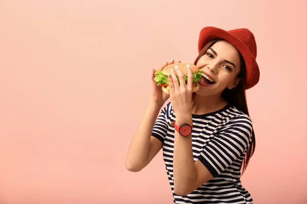 Νεαρή Γυναίκα Τρώει Νόστιμο Burger Έγχρωμο Φόντο Χώρο Για Κείμενο — Φωτογραφία Αρχείου