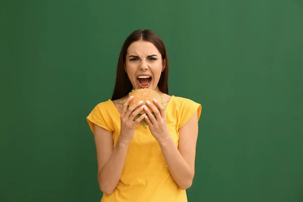 Mujer Joven Comiendo Sabrosa Hamburguesa Fondo Color —  Fotos de Stock