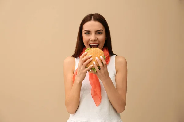 Mujer Joven Comiendo Sabrosa Hamburguesa Fondo Color — Foto de Stock