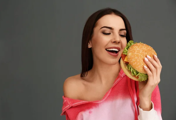 Mujer Joven Comiendo Sabrosa Hamburguesa Sobre Fondo Gris Espacio Para — Foto de Stock