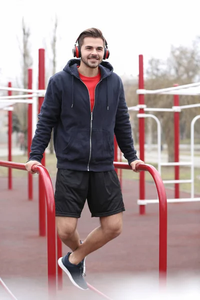 Jeune Homme Avec Casque Écoutant Musique Faisant Exercice Sur Terrain — Photo