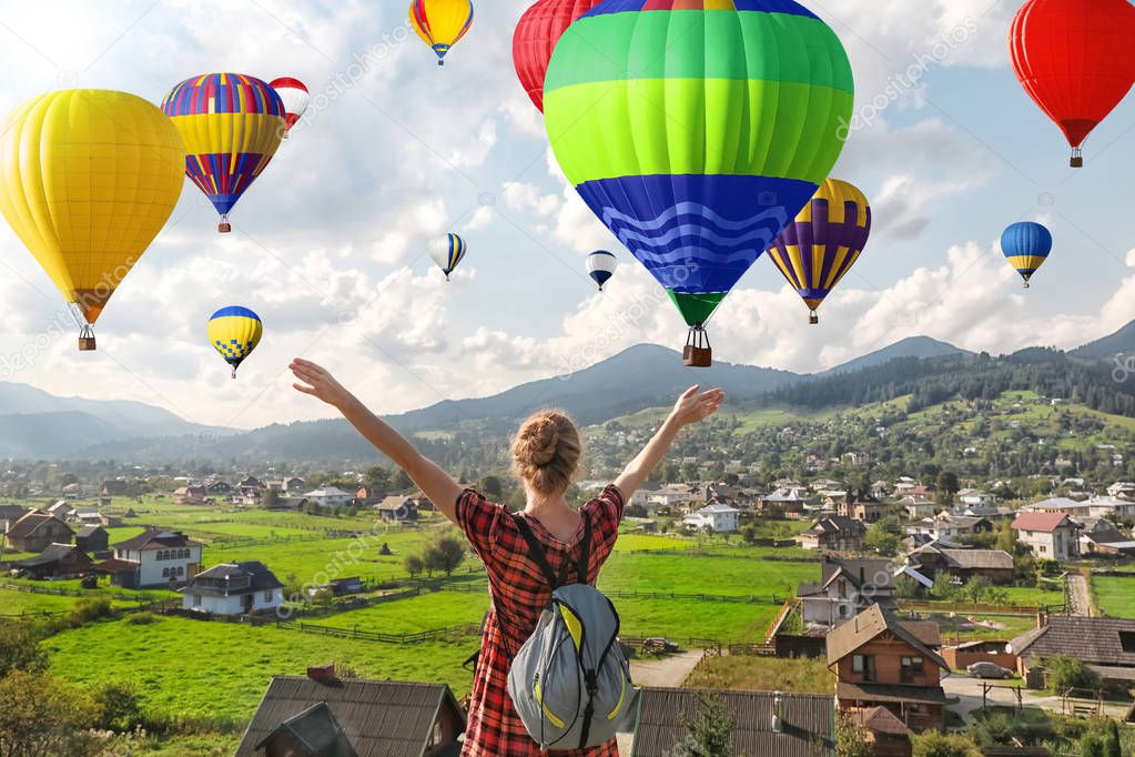 Woman enjoying beautiful view of flying air balloons 