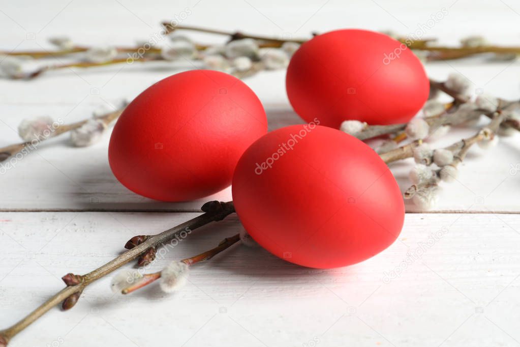 Red dyed Easter eggs and pussy willow on wooden table, closeup