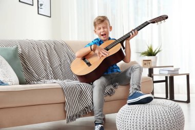 Sevimli küçük çocuk odasında kanepede gitar çalmak