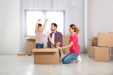 Karton kutunun içinde yeni evleri ile oynarken mutlu bir aile. Taşınma günü