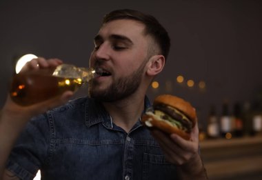 Kafede lezzetli hamburger yeme bira ile genç adam