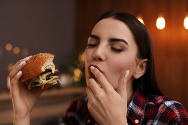 Genç kadın kafede lezzetli hamburger yemek