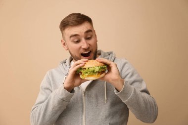 Genç adam renk arka plan üzerinde lezzetli hamburger yeme