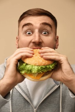 Genç adam renk arka plan üzerinde lezzetli hamburger yeme