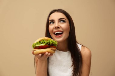 Genç kadın renk arka plan üzerinde lezzetli hamburger yemek