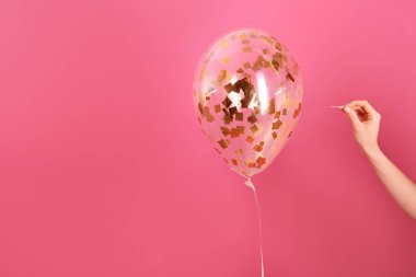 Kadın renk arka plan, closeup iğne ile balon piercing. Metin için yer