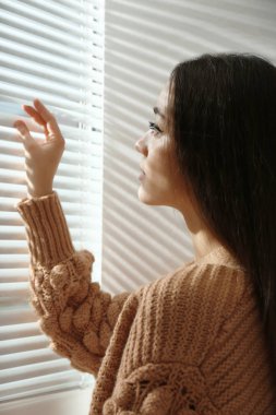 Evde genç kadının açılış pencere güneşlikler