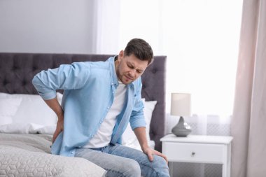 Evde sırt ağrısı çeken genç bir adam.